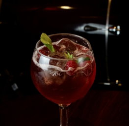 a glass filled with a drink sitting on top of a wooden table